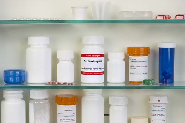 An open medicine cabinet containing pill bottles of various colors and sizes.