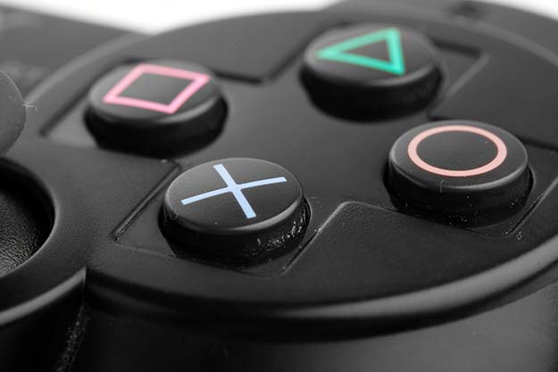 Close-up of the four buttons on a black PlayStation remote.