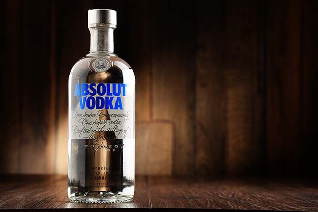 A bottle of Absolut vodka in front of a wood textured background.