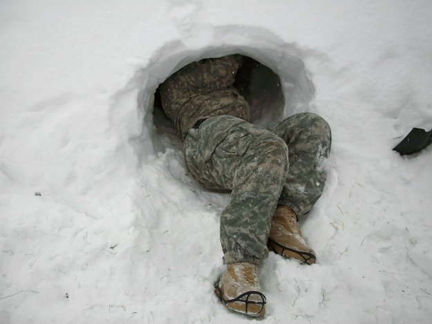 snow-cave-with-man-in-camo-half-inside Snow Shelter: Learn How to Build a Snow Cave For Winter Survival