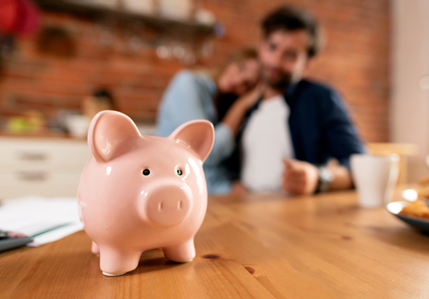 Happy Couple Looking at the Piggy Bank | 52-Week Savings Plans that Work and Why You Need One