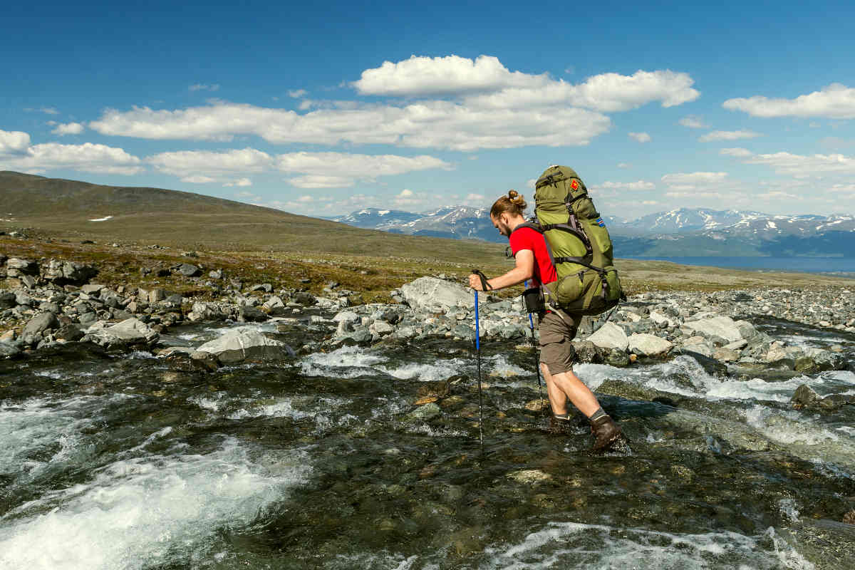 Hiker is crossing the river in Sweden | Hiker in Caucasus mountain | Good Reasons To Carry A "Survival Stick" | survival hiking stick