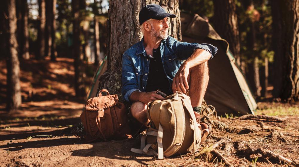 portrait senior man sitting under tree | Wilderness DIY: How to Make Your Own Bushcraft Camp Chair | featured