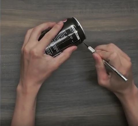 Hands cutting off the top of a Pepsi can with an Exacto knife.