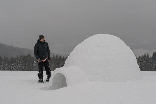 snow-sheter-with-man-standing-outside Snow Shelter: Learn How to Build a Snow Cave For Winter Survival