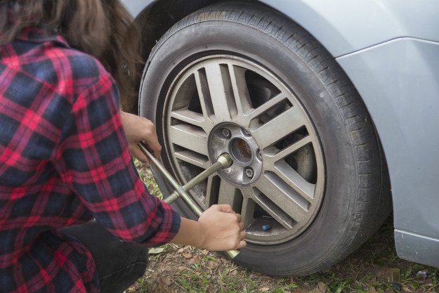 girl-changing-tire Survival Emergency Car Kit | The DIY Kit That Could Save Your Life