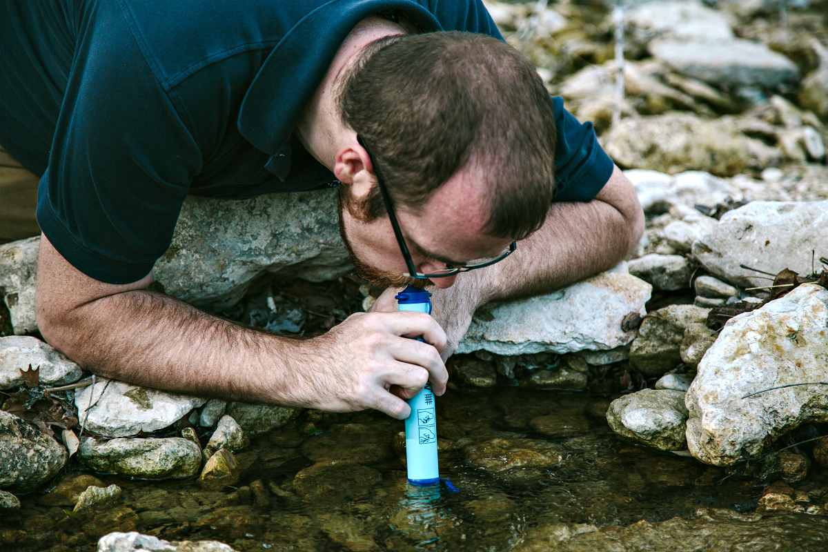 a man using a water filter | Best Survival Gear