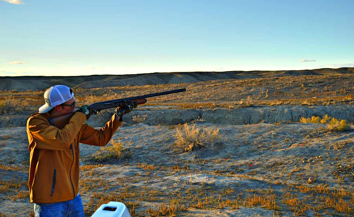 A man wearing yellow jacket firing a shotgun | These Hunting Shotguns Are The Best Bang For Your Buck