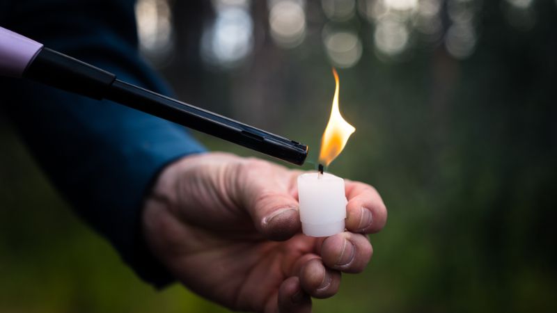 hand-lighting-wax-candle-stub-using camping