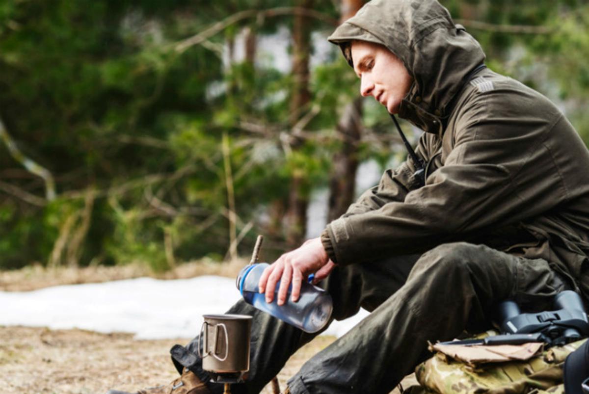 Hunter cooking food with a portable gas burner | Coffee Can Survival Kit: Don't Travel Without It