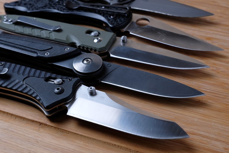 Folding knives on a wooden background. | pen knife self defense