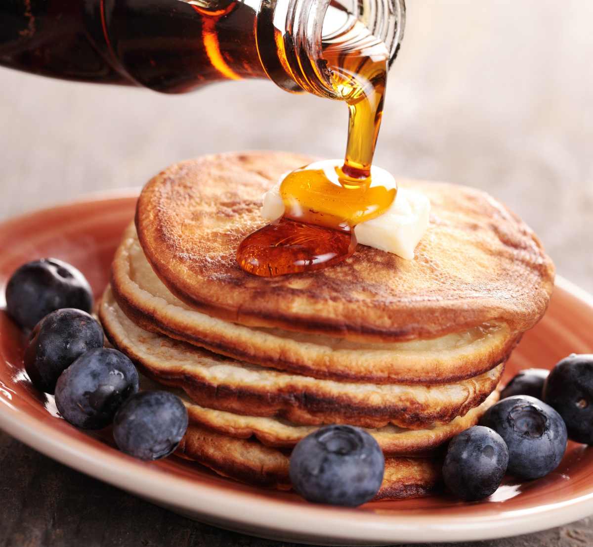 Close-up of pouring maple syrup on stack of pancakes | Survival Food Items That Will Outlast The Apocalypse