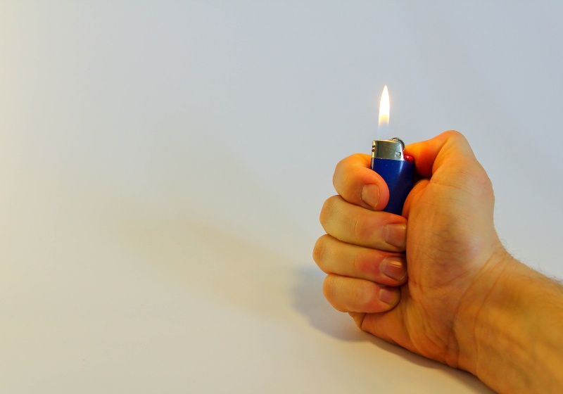 hand burning lighter on white background | edc survival kit