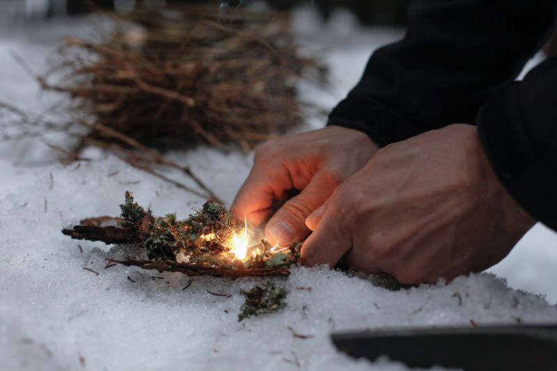 man-lighting-fire-dark-winter-forest survival hacks 