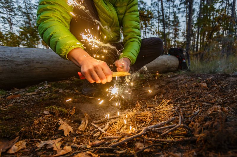 man-outdoors-makeing-fire-by-flint survival hacks 