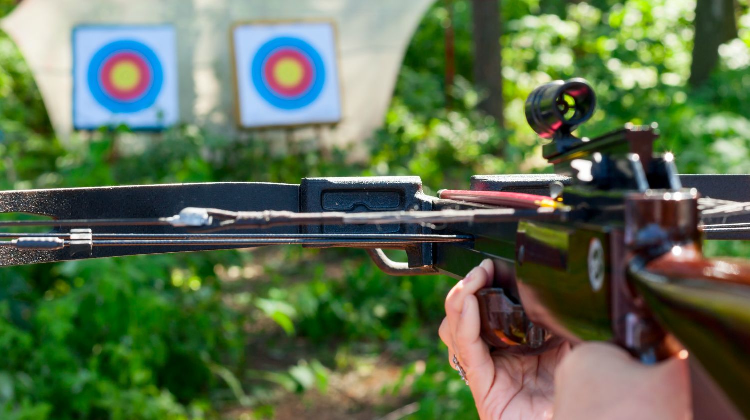 Woman aiming crossbow at target outdoor | How To Use A Crossbow And Why Use It Over Guns | Featured