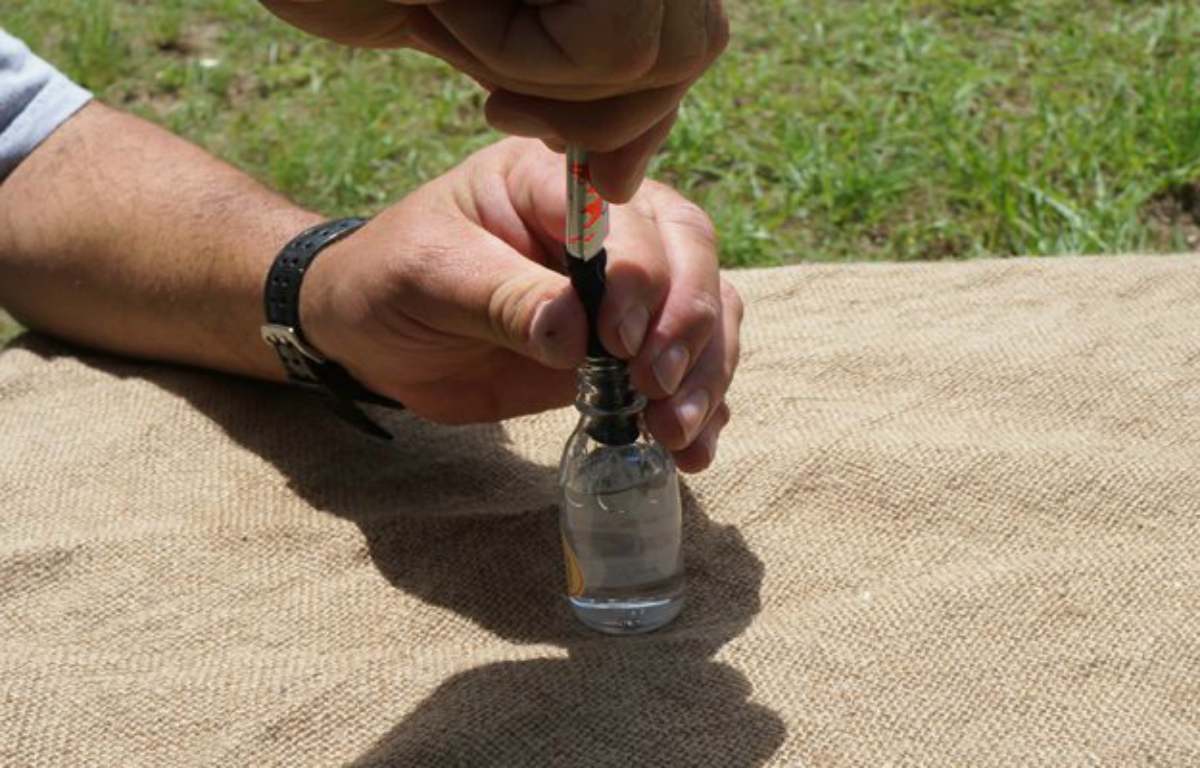 Putting aluminum in the bottle | How To Make An Improvised Camping Lantern 