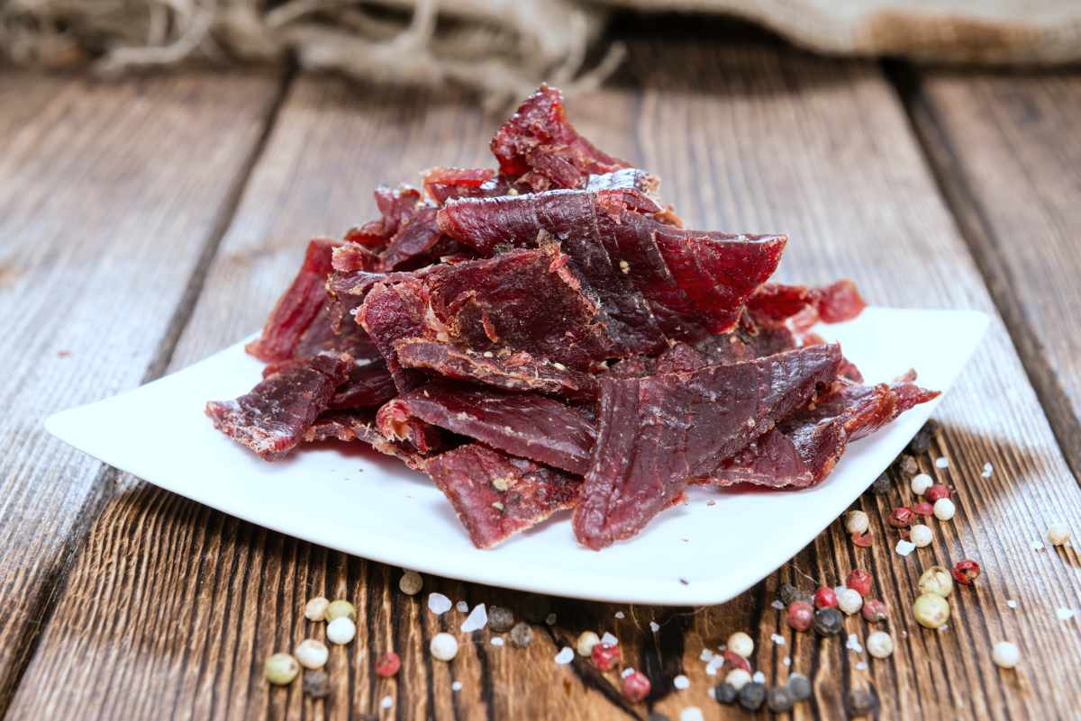 portion of beef jerky on wooden background | DIY Survival Food You’ll Actually Want To Eat | survival food | emergency food