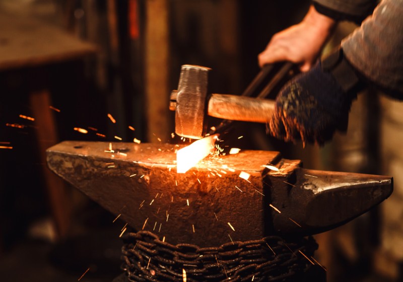 blacksmith manually forging redhot metal on | blacksmith forge