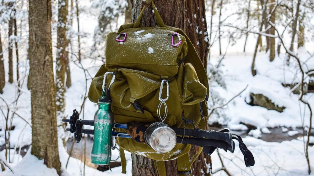 hikers backpack hanging tree | Winter Survival Gear | Winterize Your Bug Out Bag | featured
