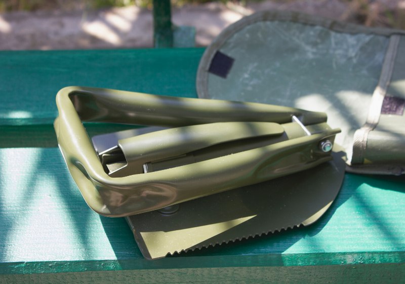 military spade folded on green bench | extreme cold weather work gear
