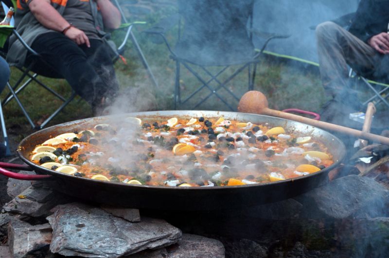 persons-sitting-outside-tent-making-paella | campfire paella