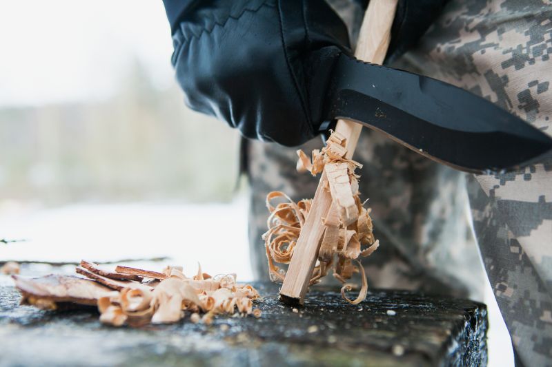 man prepares woodwool hunting knife starting survival knife brands