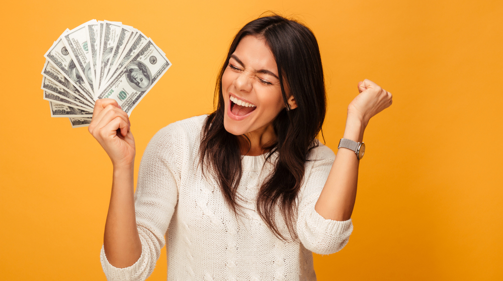 Young Woman Holding Money | 52-Week Savings Plans that Work and Why You Need One
