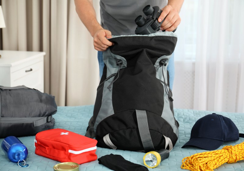 man packing different camping equipment into | incase city backpack