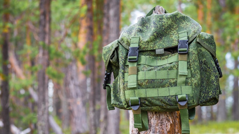 small backpack hanging on trunk tree | How To Turn Your Bug Out Bag Into A Minimalist Backpack | featured