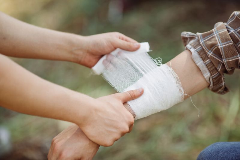 person-wrapping-his-friends-injured-arm | first aid