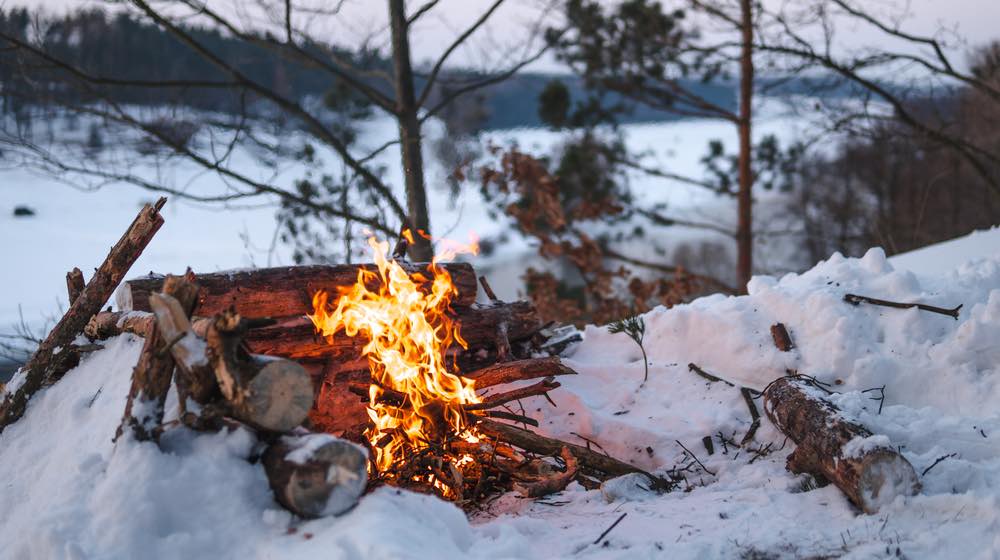 Campfire burns in the snow in the forest hill, campfire burning in cold winter | How To Make Fire From Ice | featured - ss