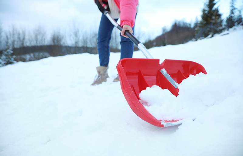 woman cleaning snow shovel outdoors on | how to build a quinzee