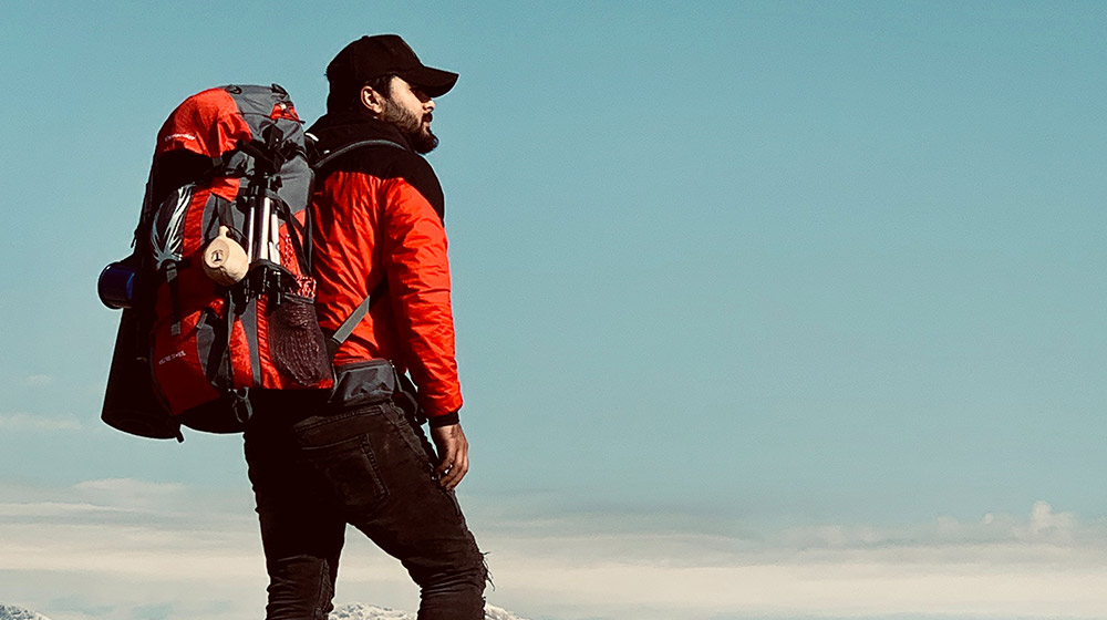 man standing on cliff edge - backpacking checklist - featured
