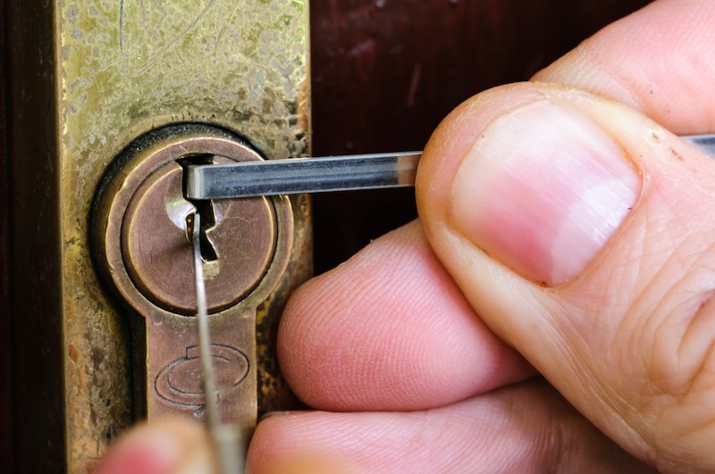 A man uses lockpicking tools to pick the lock of a house | locksmith