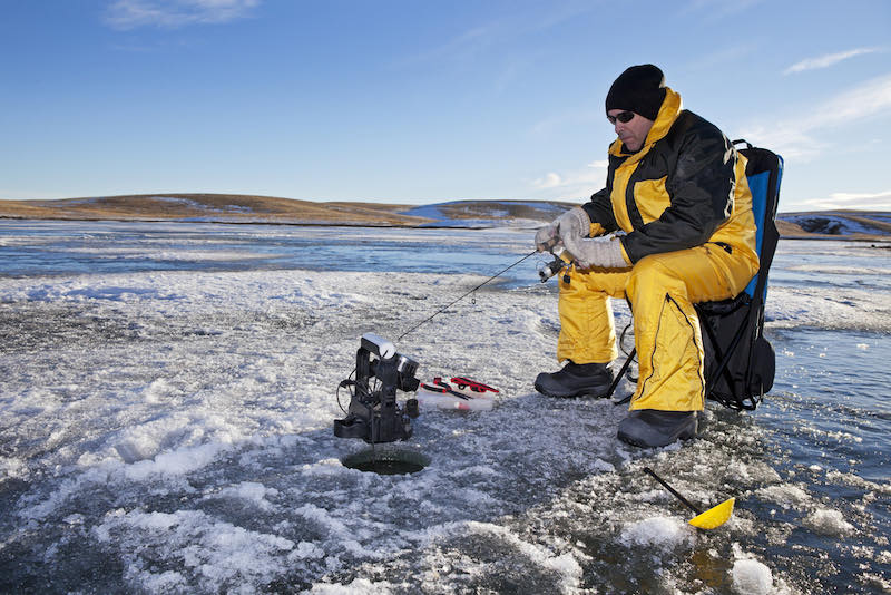 Man ice fishing on a frozen Canadian lake | ice fishing rod