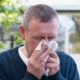Portrait of middle aged european man blow nose on backyard background in sunny spring day | spring allergy | featured ss