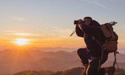 Young man with backpack and holding a binoculars | Best Compact Binoculars For People On The Go | Featured