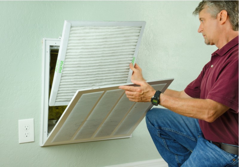 home owner installing a clean new air filter on a house air conditioner which is an important part of preventive maintenance. | keep your home clean and pollen-free | ss