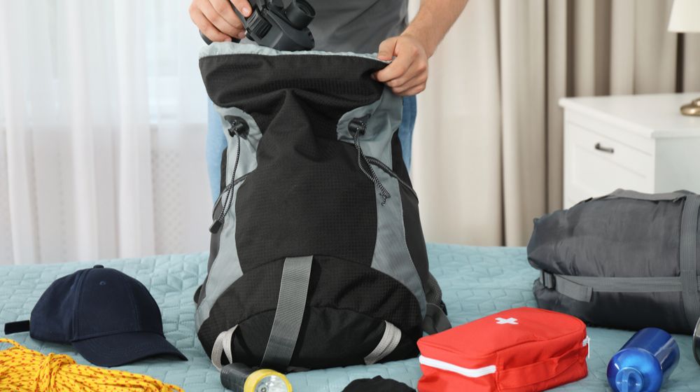 man-packing-different-camping-equipment-into Things You Need To Survive | Featured
