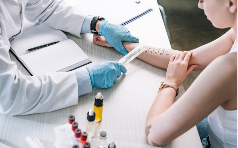 overhead view of allergist holding ruler near marked hand of woman | see an allergist | spring allergies