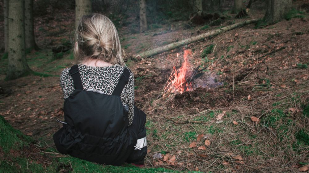 young-girl-sitting-forest-near-bonfire raising preppared children | Featured