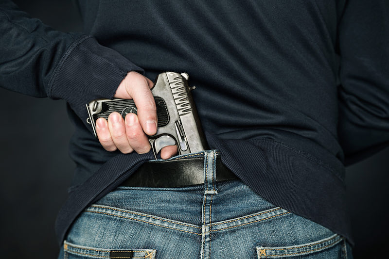 A person is hiding a handgun under the denim belt | emergency bag contents