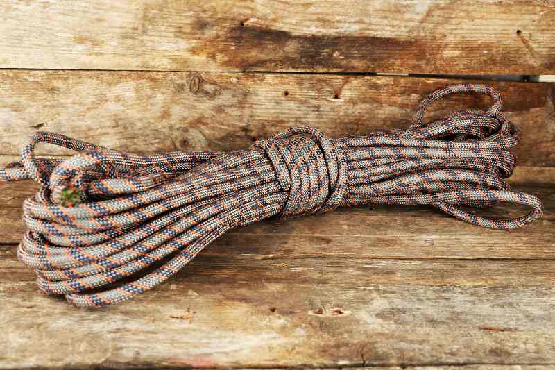 Cuerda de escalada sobre fondo de madera kit de supervivencia de bolsillo