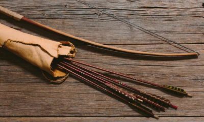 Close up shot of bow laying beside arrows in a leather quiver on wooden planks | DIY BOW AND ARROW | FOLLOW THESE SIMPLE STEPS | Featured