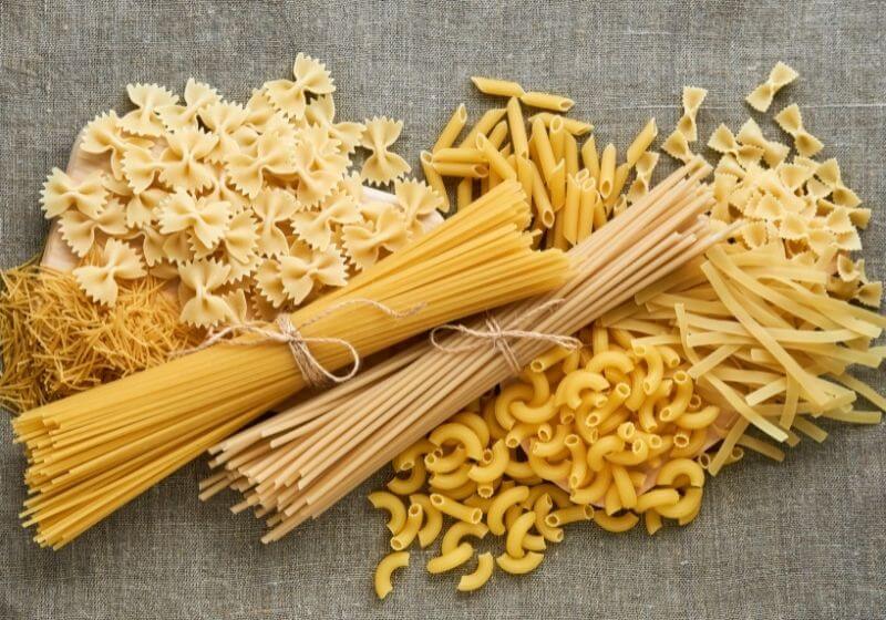 Different types of raw pasta on a textile background Foods to stock up on SS