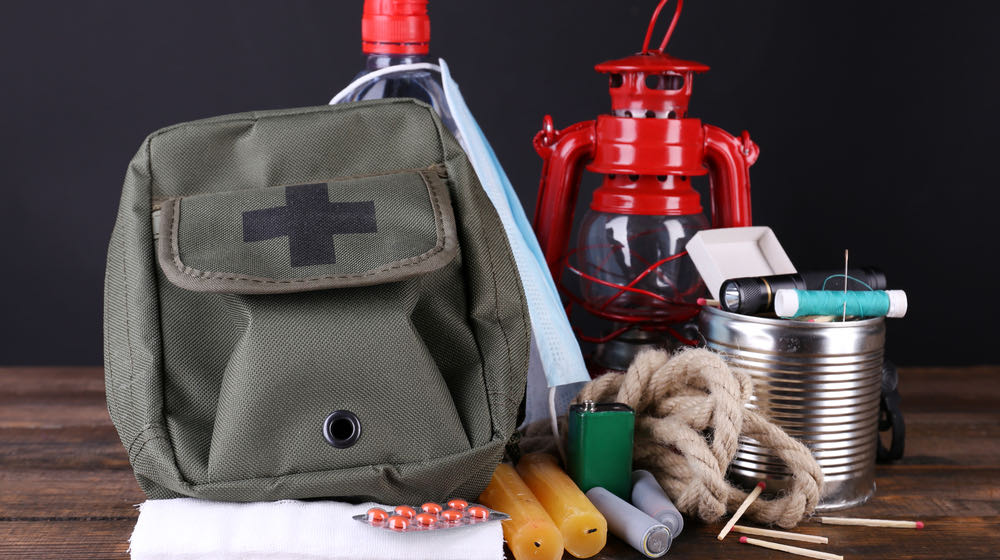 Emergency preparation equipment on wooden table, on dark background | Items to Pack in an Emergency Bag | featured