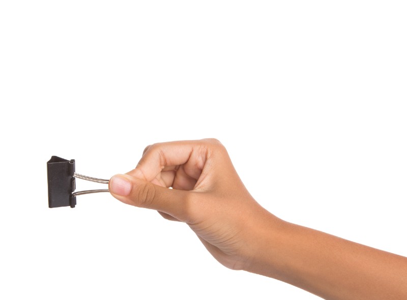 Female hand holding binder clip over white background-binder clip