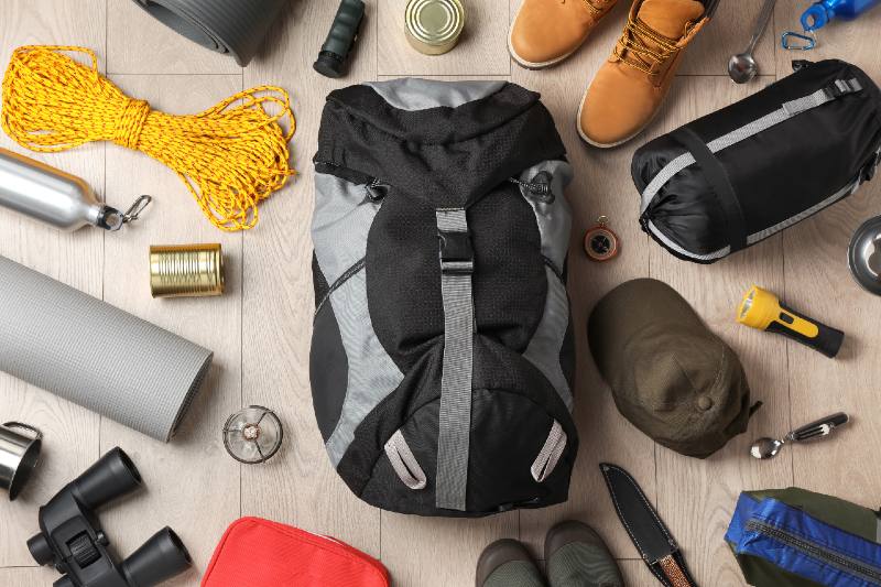 Flat lay composition with different camping equipment on wooden background-BUDGET SURVIVAL KIT