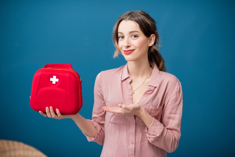 Portrait of a woman with first aid kit on the blue wall background-IFAK